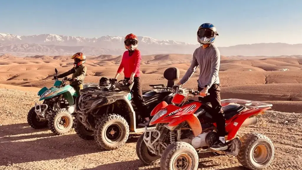 Un quad sur une piste du désert d'Agafay avec les montagnes de l'Atlas au loin